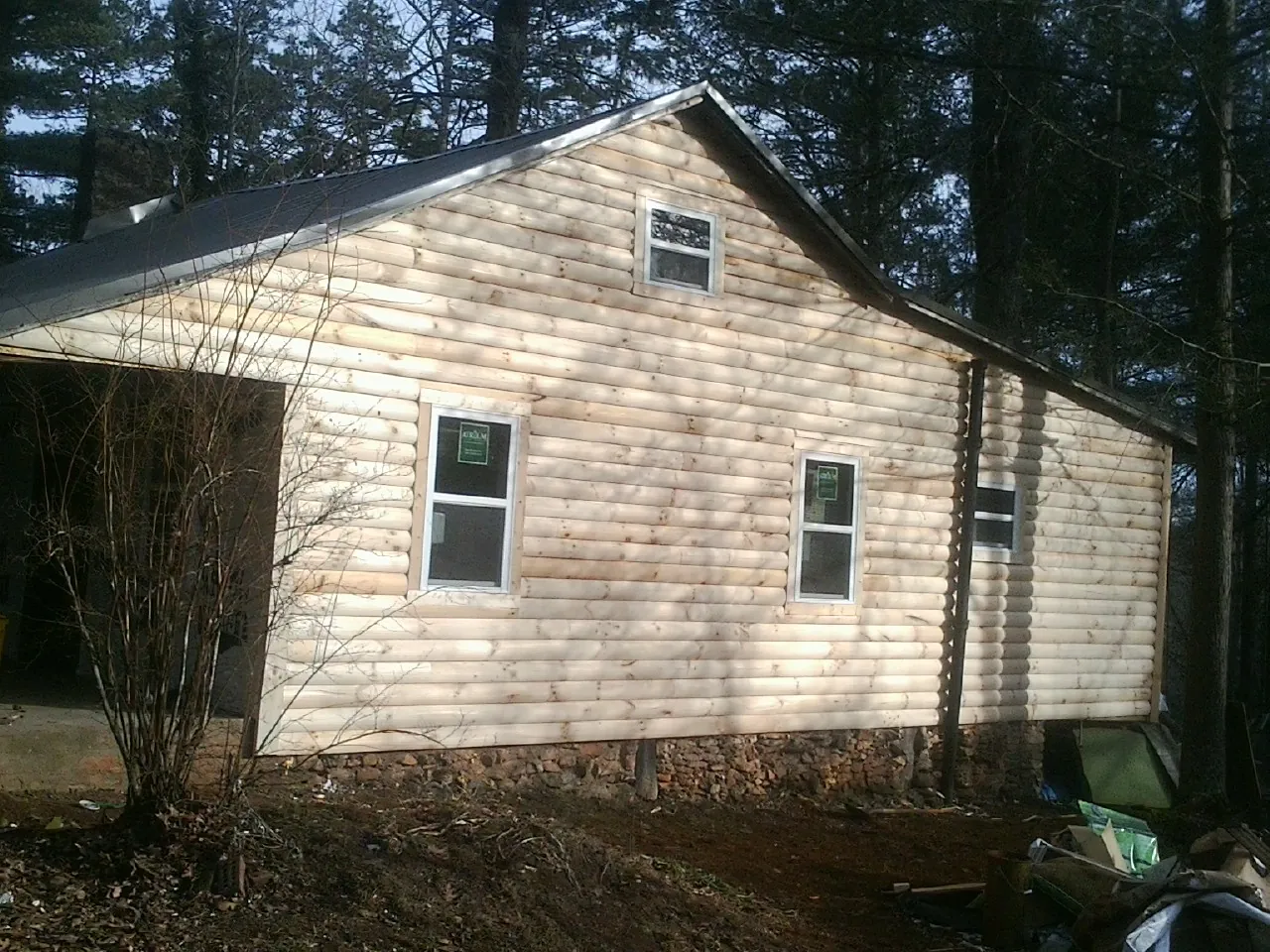 New log siding and dark metal roofing on a gable end in Oak Ridge
